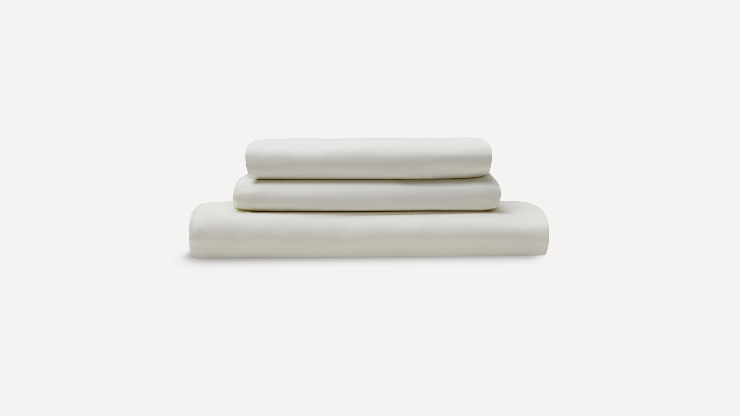 Three neatly folded cream-colored bed sheets stacked, displayed against a plain white background.