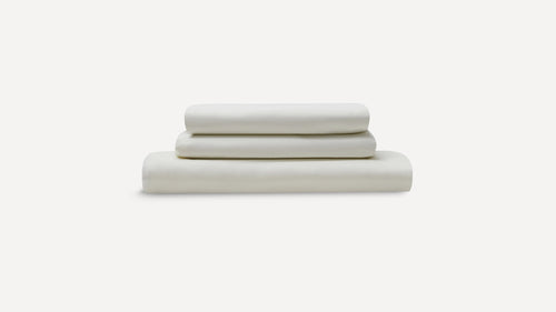 Three neatly folded cream-colored bed sheets stacked, displayed against a plain white background.