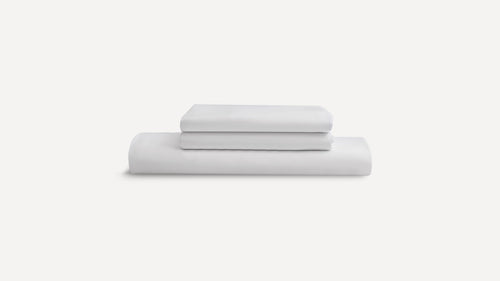 Stack of three neatly folded white bed sheets against a plain white background.