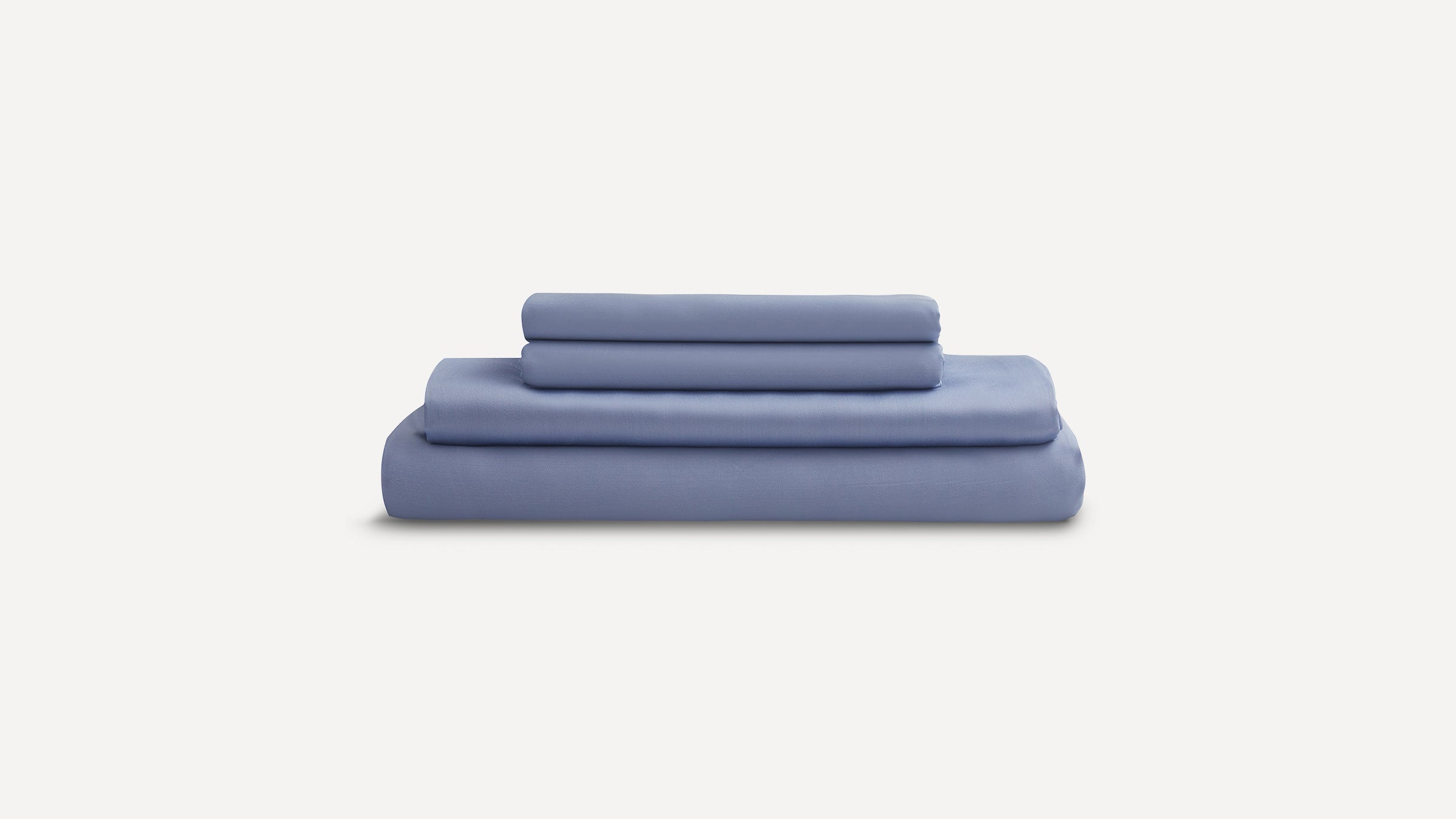Stack of neatly folded light blue bed sheets and pillowcases on a plain white background.