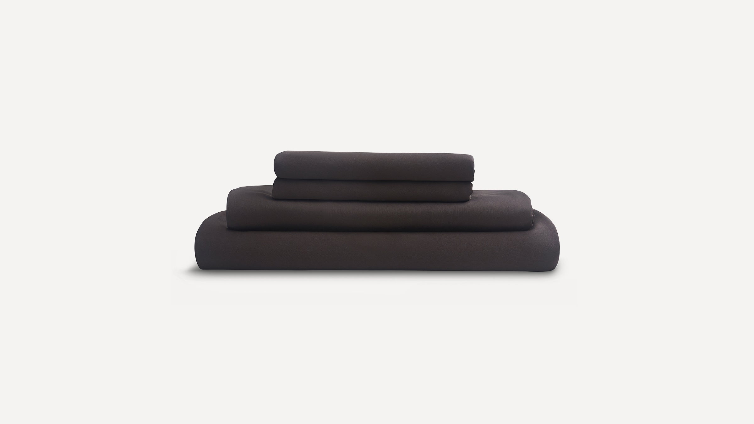Set of dark grey folded bed sheets including fitted sheet, flat sheet, and pillowcases, displayed on white background.