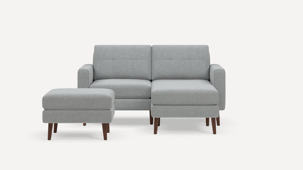 Light grey fabric loveseat with matching ottoman, tufted back cushions, rounded arms, and wooden legs on a white background.