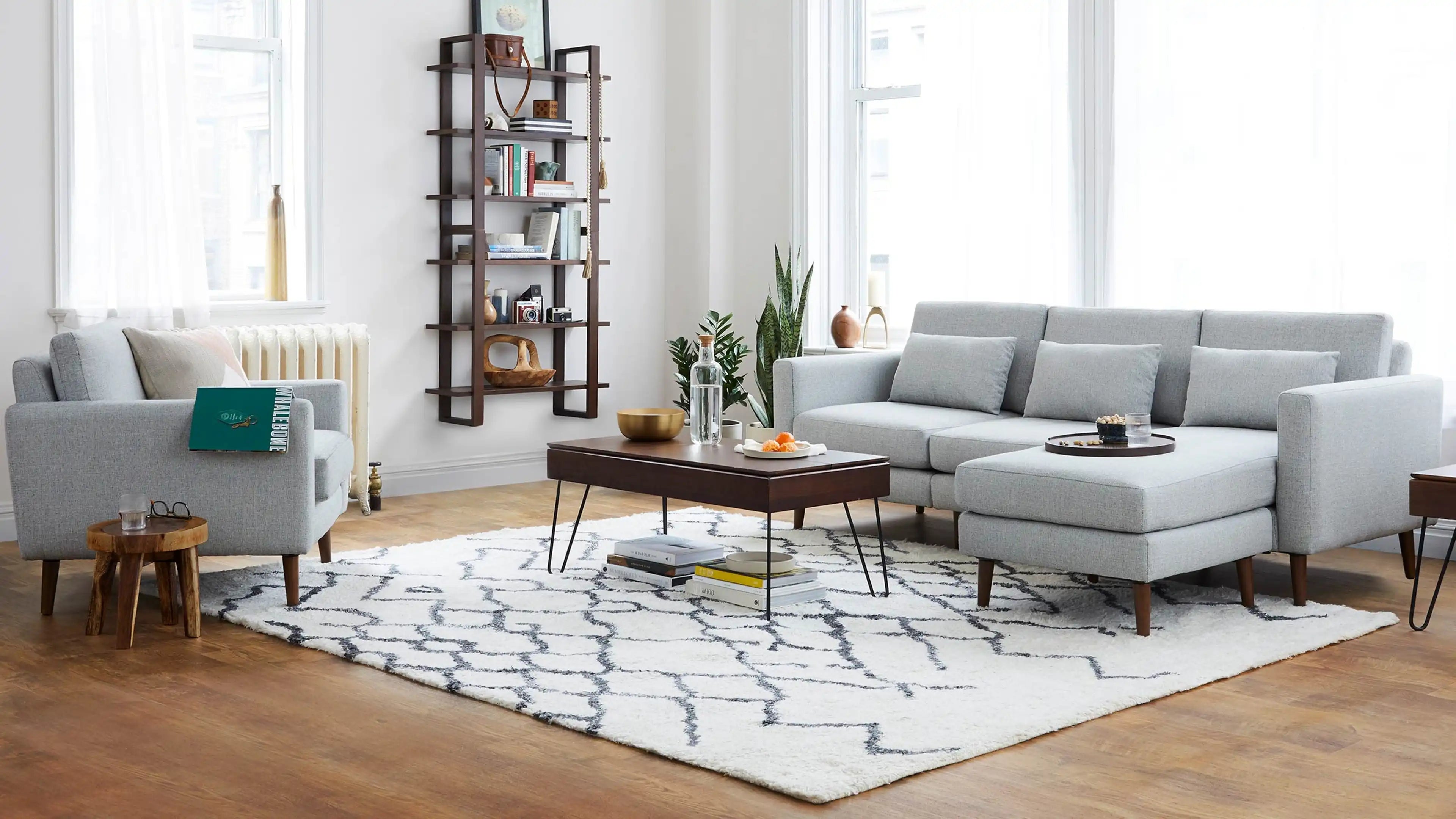 modern living room with light gray sofa, light gray armchair, dark wood coffee table, and white rug
