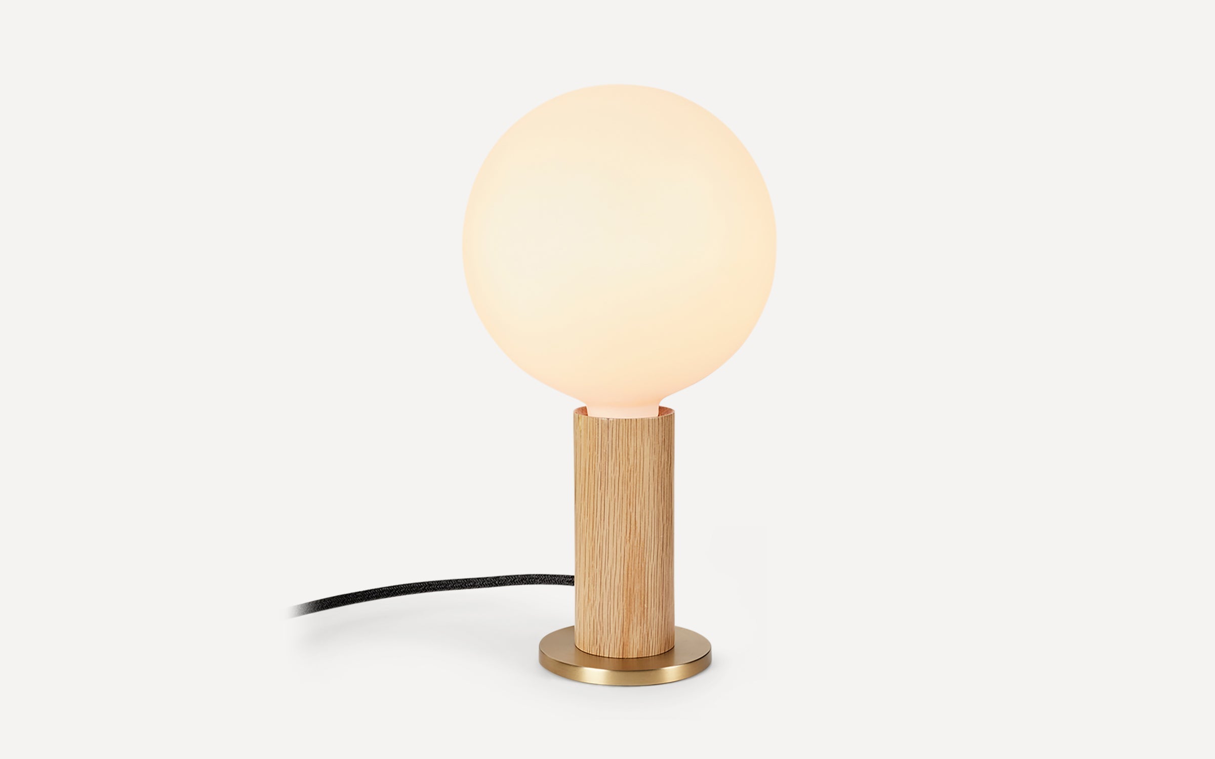 Modern table lamp with a frosted round glass shade, wooden cylindrical base, and brass metal bottom plate.