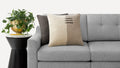 a gray couch with a pillow and a plant on the side table