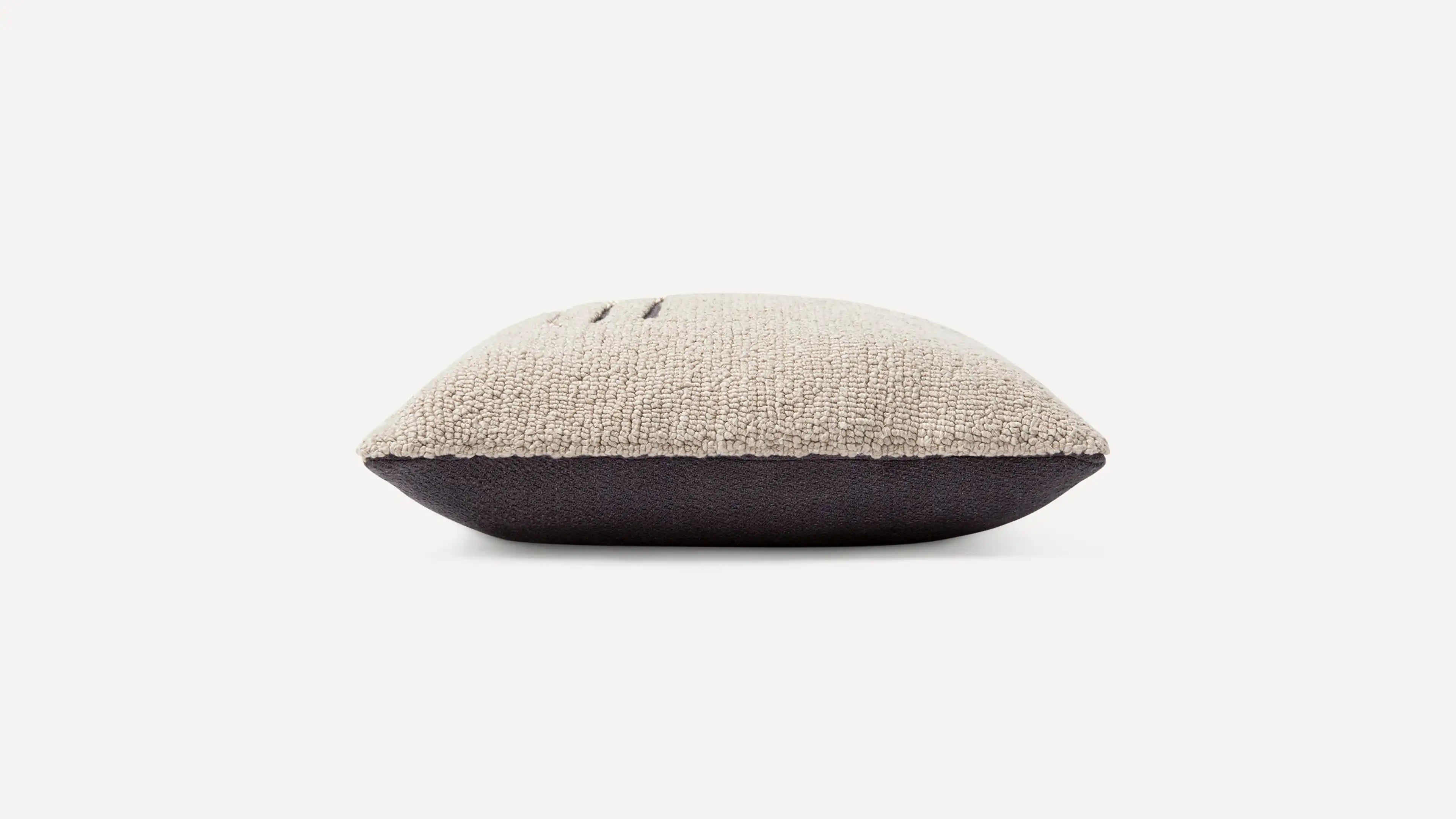 a beige and black cushion with a black pillow on top