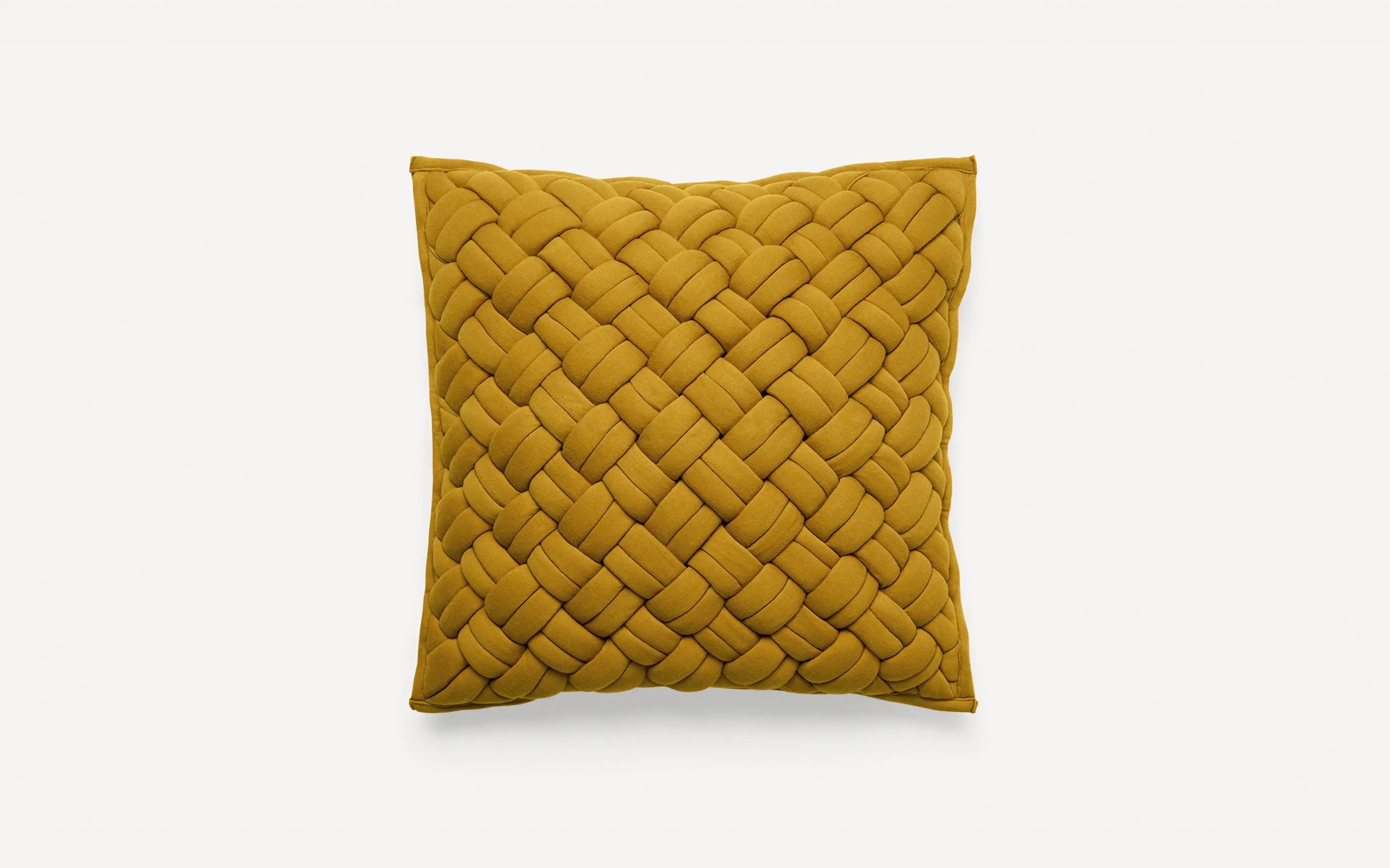 a mustard yellow cushion with braiding on the front