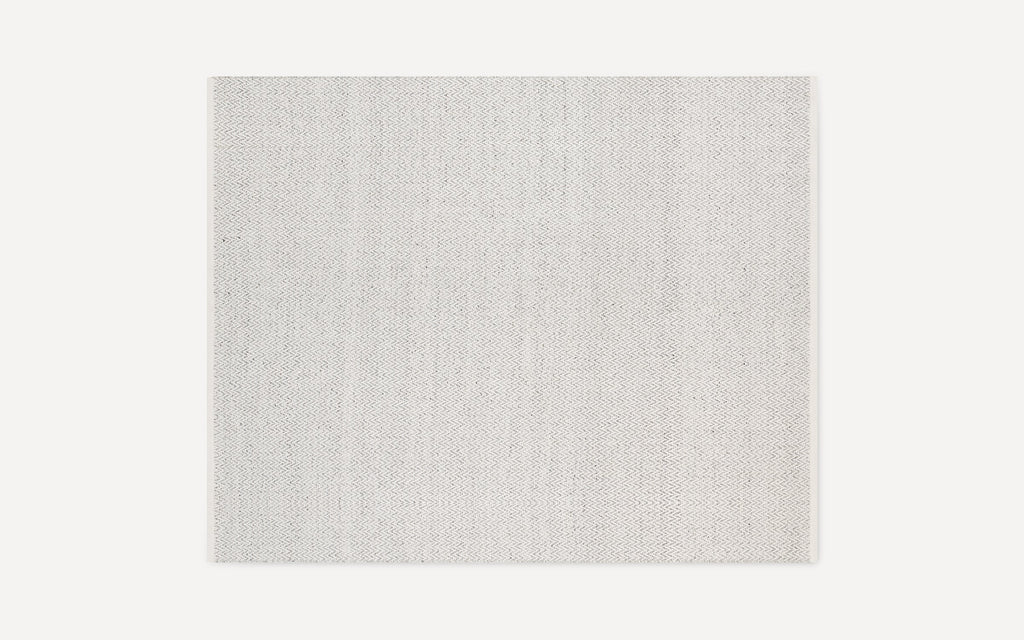 Rectangular light gray rug with a subtle herringbone pattern, flat woven texture, and clean, finished edges.