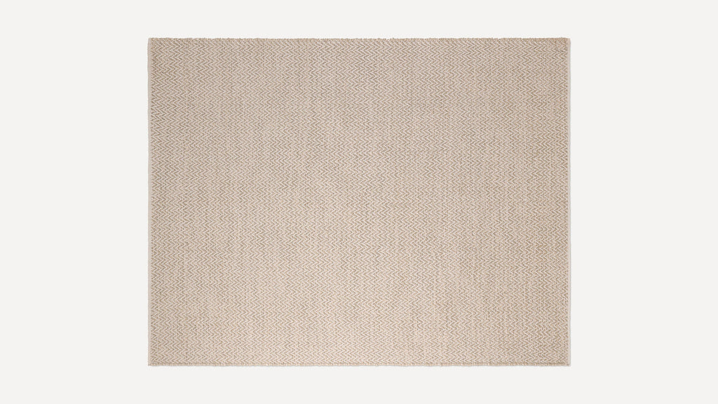 Beige woven rug with a subtle zigzag pattern in natural fiber, rectangular shape, and flat texture.