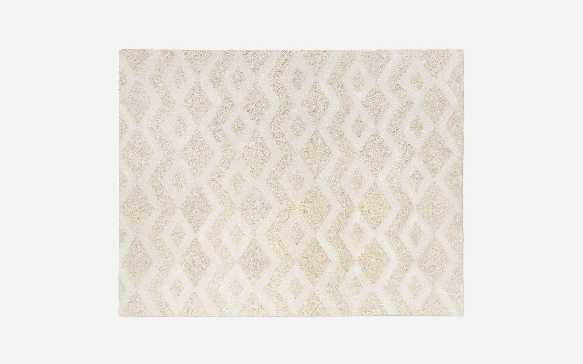 Beige and cream area rug with a soft texture, featuring an interlocking diamond geometric pattern.