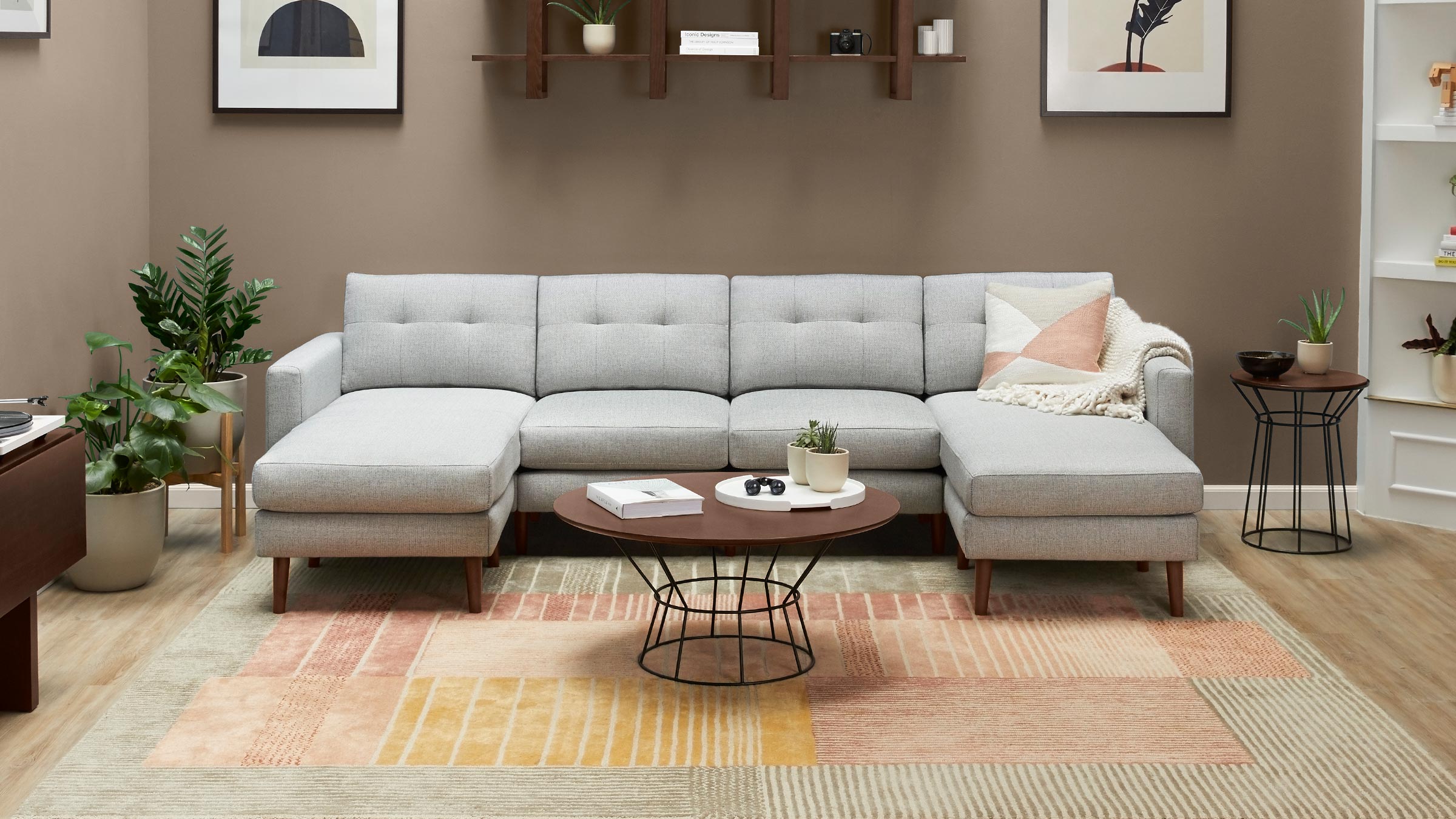 modern gray sectional sofa with tufted cushions and wooden legs, placed on a beige rug, surrounded by a wooden coffee table and plant