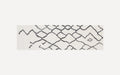 Long rectangular white rug with a black abstract geometric diamond pattern and a soft, plush texture.