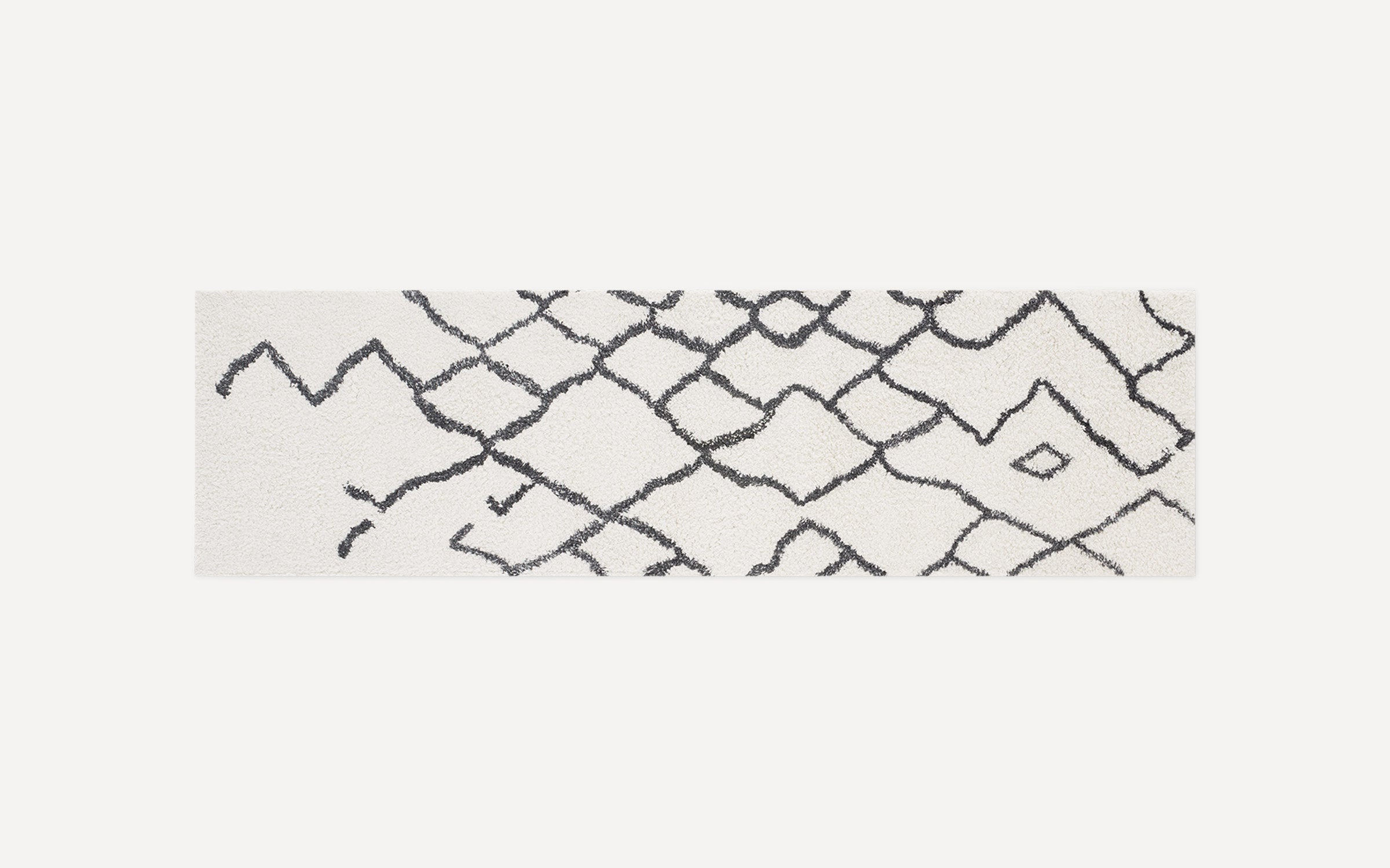 Long rectangular white rug with a black abstract geometric diamond pattern and a soft, plush texture.