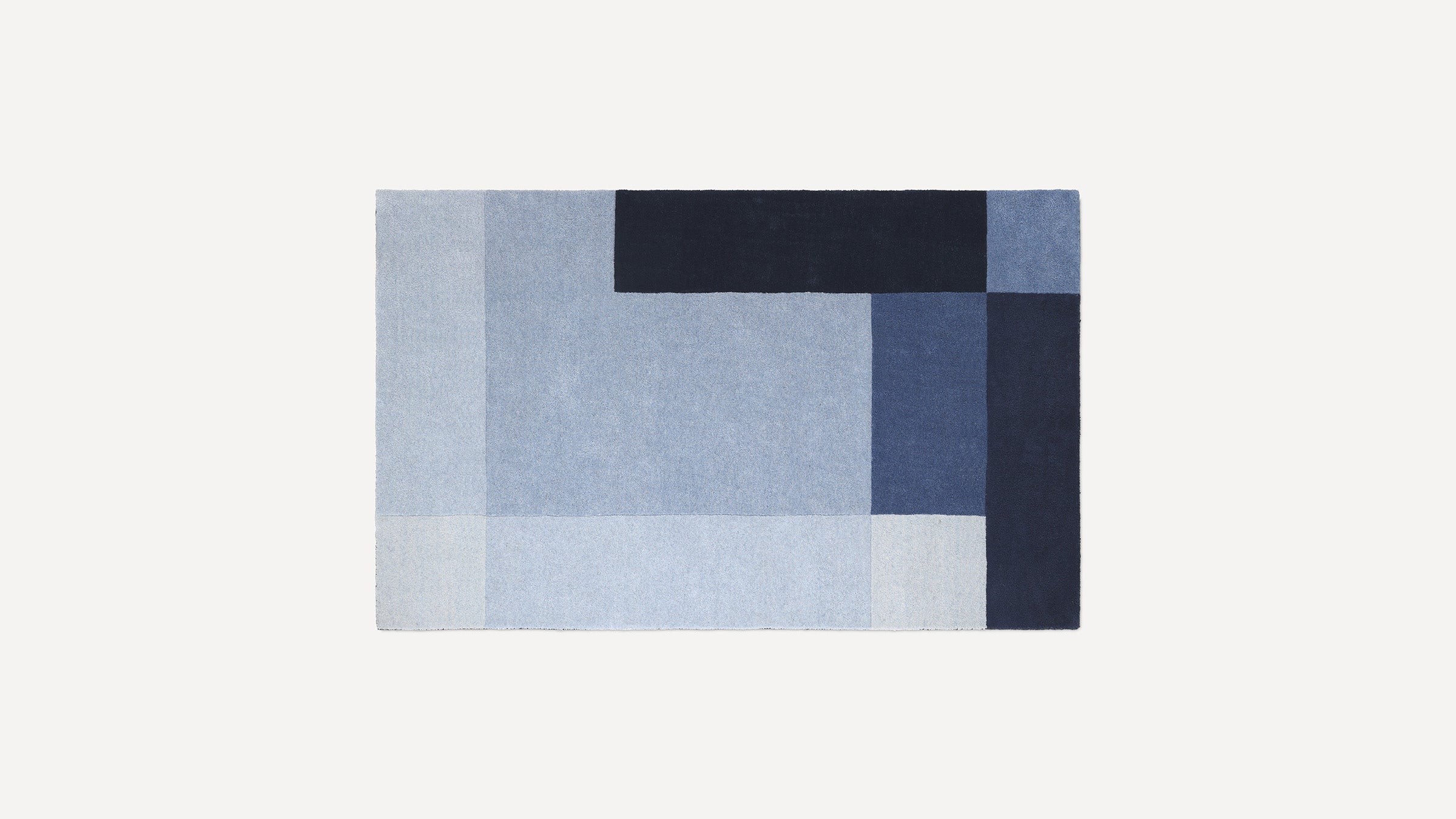 Rectangular rug with a geometric pattern in various shades of blue, including light, medium, and dark tones.