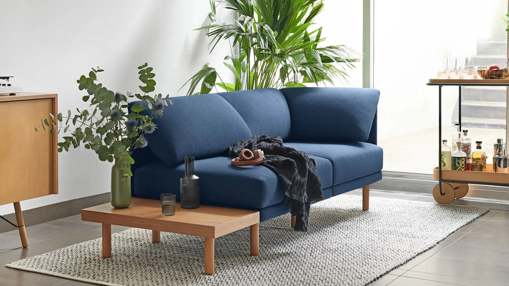 a blue sofa with plants on the side and other furniture in front