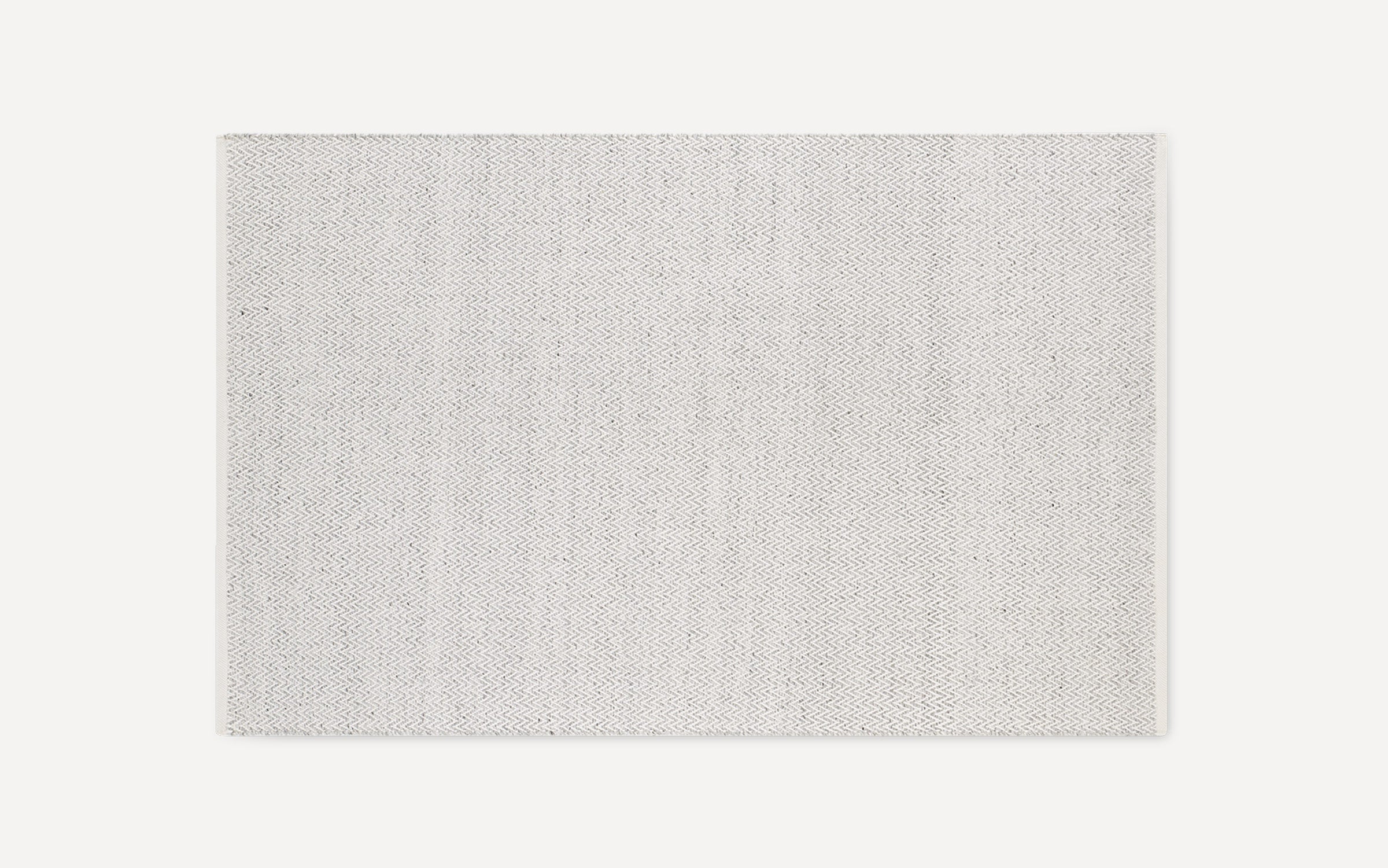 Rectangular light gray area rug with subtle small-scale woven chevron pattern, simple and modern design, flat weave texture.
