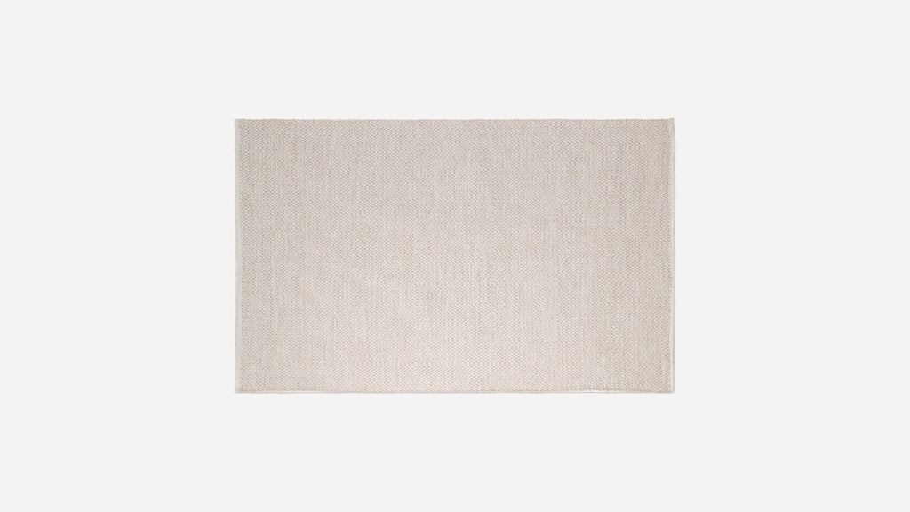 Rectangular beige woven rug with subtle herringbone pattern and fringe edges, displayed flat on white background.