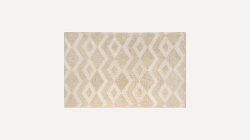 Rectangular beige rug with raised diamond and zigzag pattern, featuring a soft, plush texture.