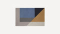 Rectangular rug with geometric color blocks in blue, navy, mustard, gray, and beige on a light background.