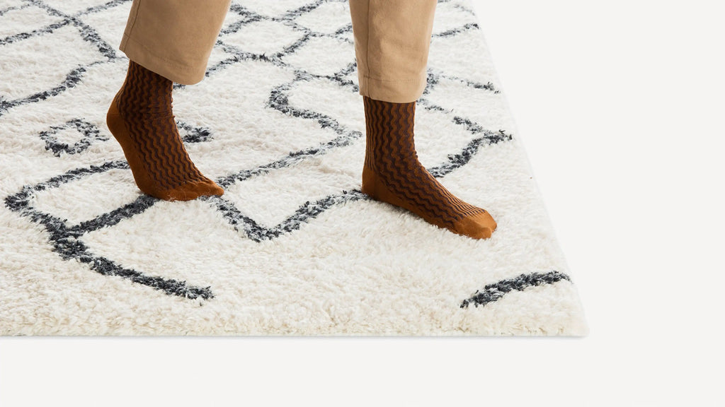 a woman in brown boots and beige pants stands on a white rug