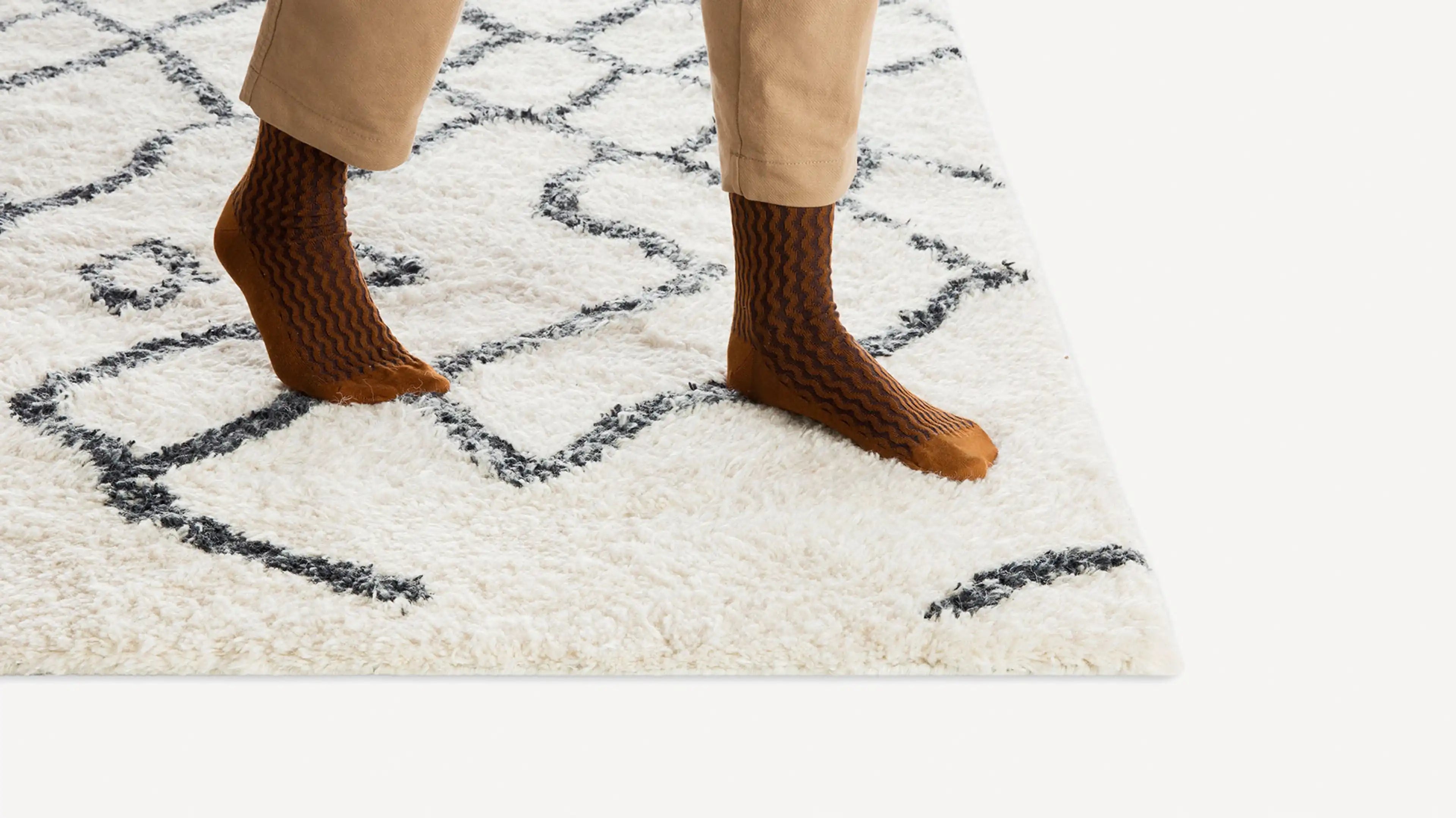 a woman in brown boots and beige pants stands on a white rug