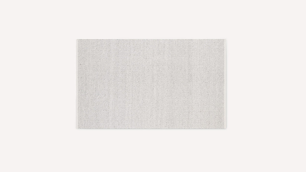 Rectangular light grey floor rug with subtle zigzag pattern and neatly finished edges on a plain white background.