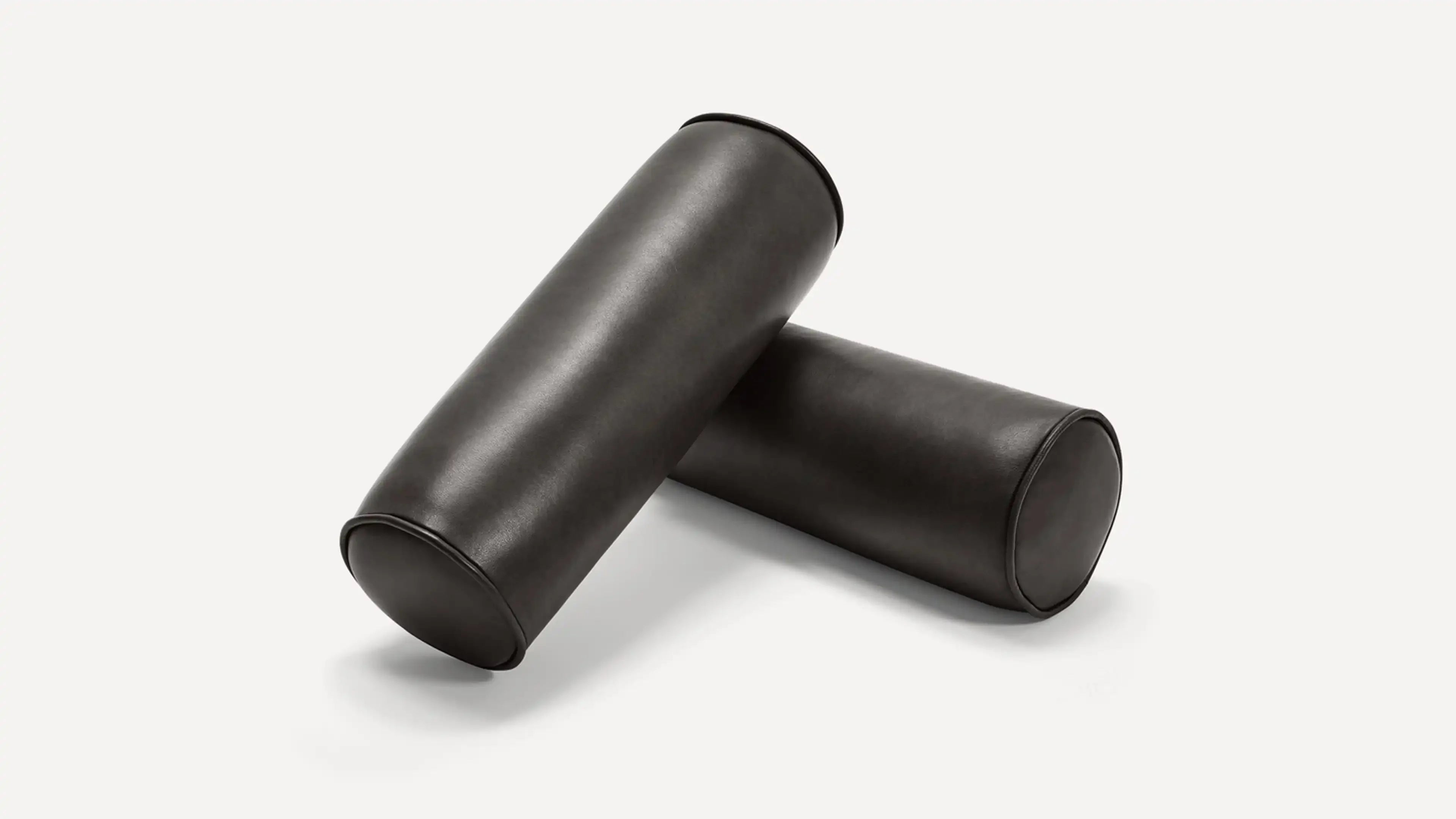Two black cylindrical leather bolster pillows arranged on a white background.