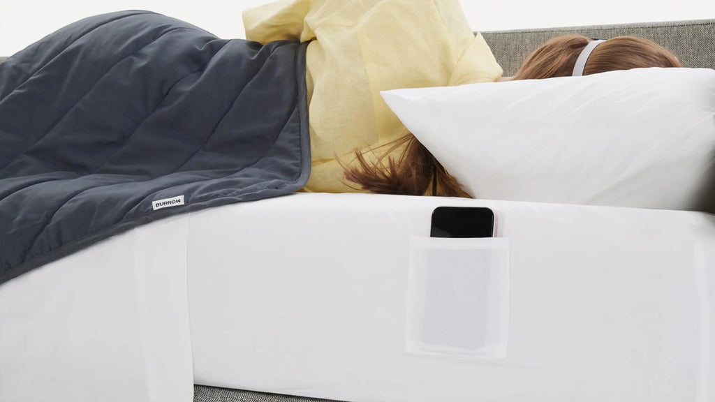 a woman laying on a couch with a pillow and phone