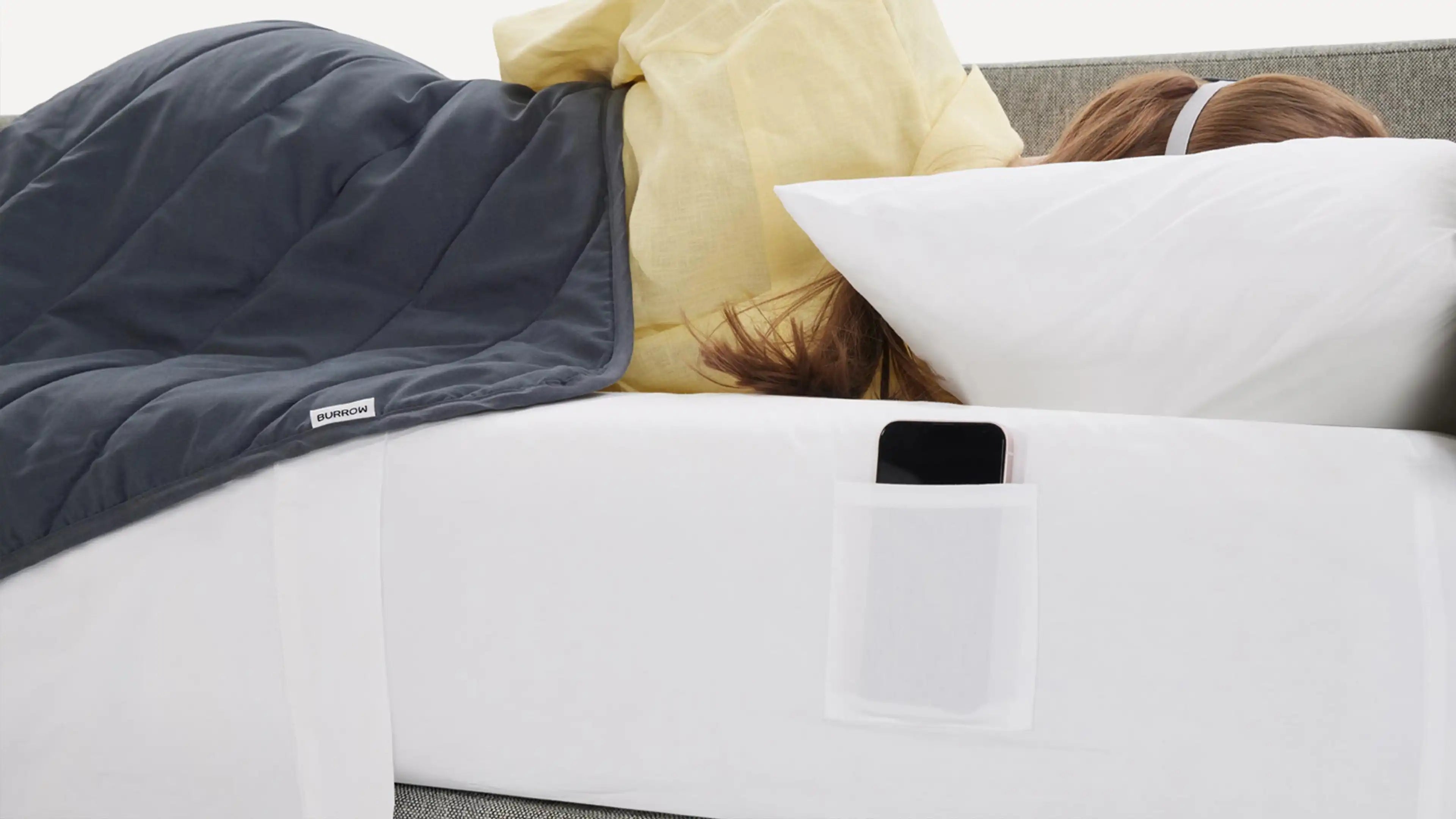 a woman laying on a couch with a pillow and phone