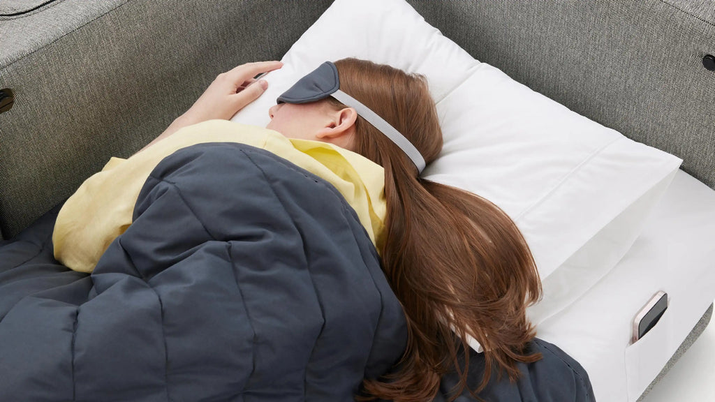 a woman sleeping on a couch with a pillow and a pair of eye glasses
