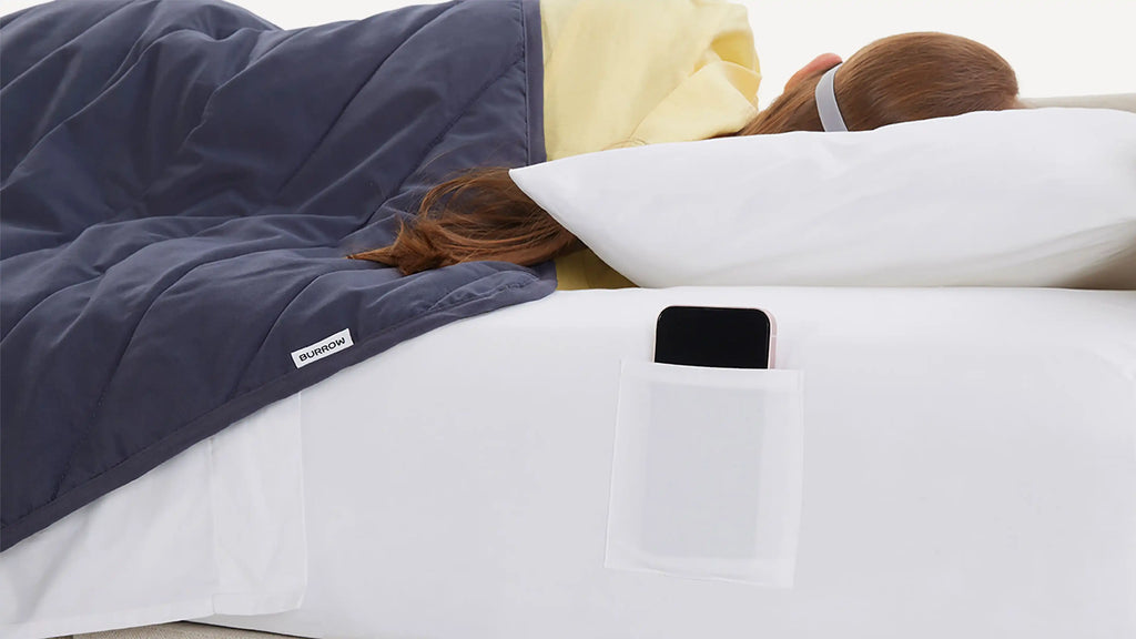 a woman laying on a bed with a phone in her pocket
