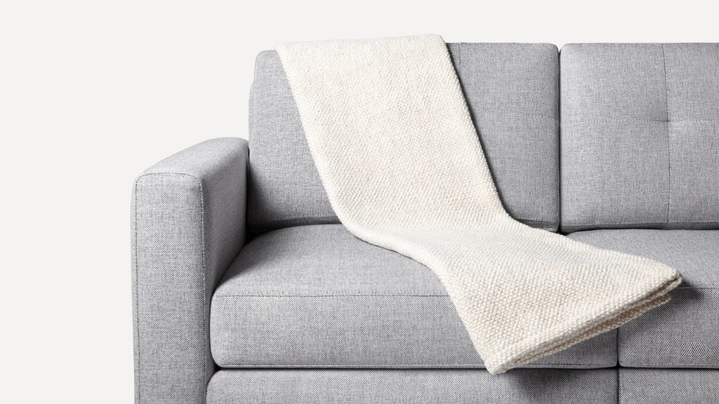 a gray couch with a white blanket on it