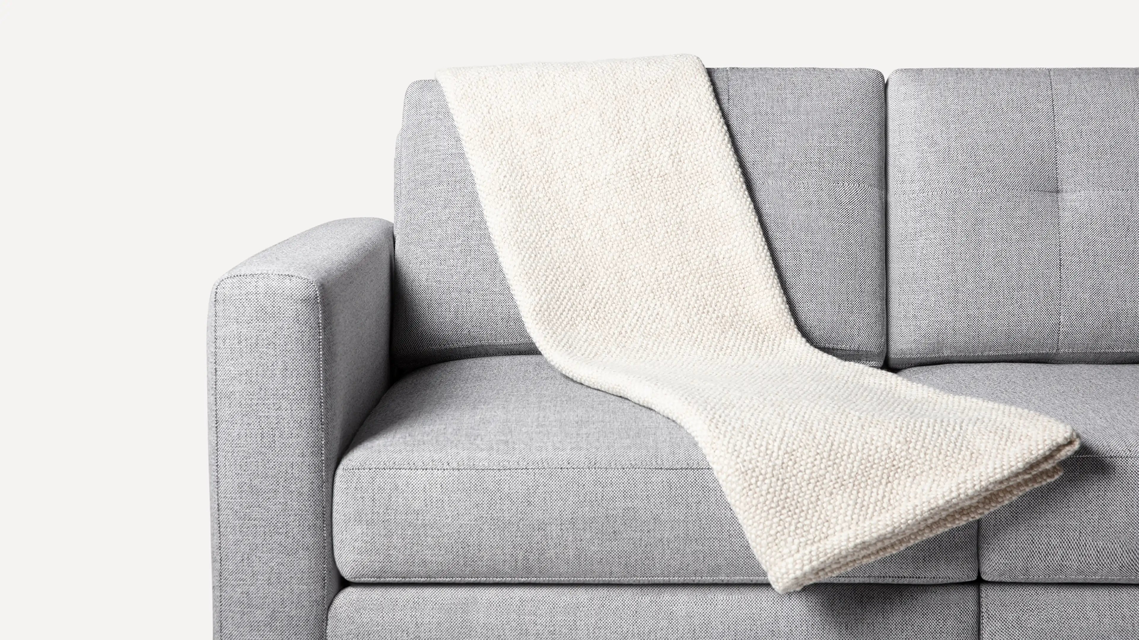 a gray couch with a white blanket on it