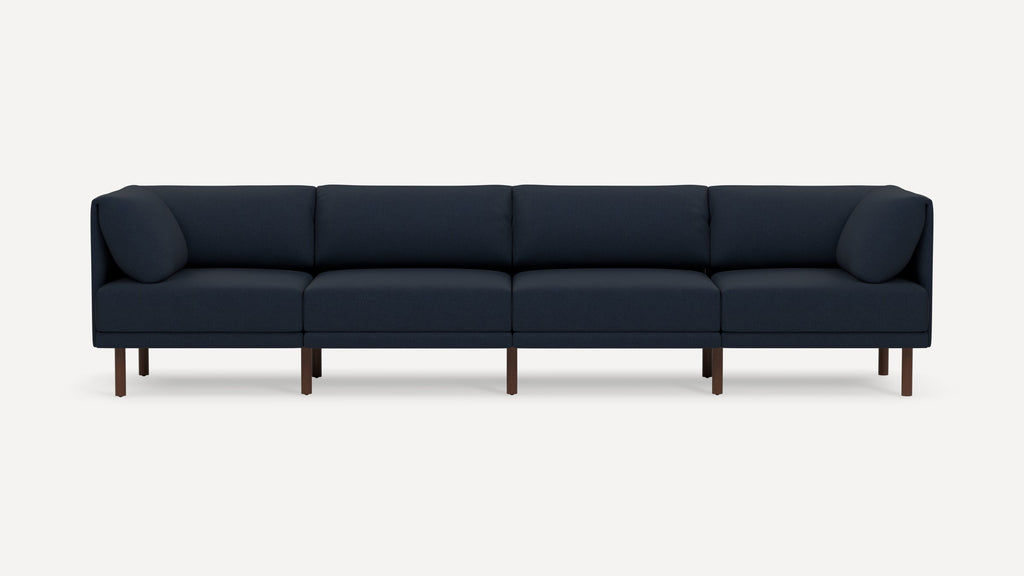 Modern navy blue fabric sectional sofa with wooden legs and four cushions, pictured against plain white background.
