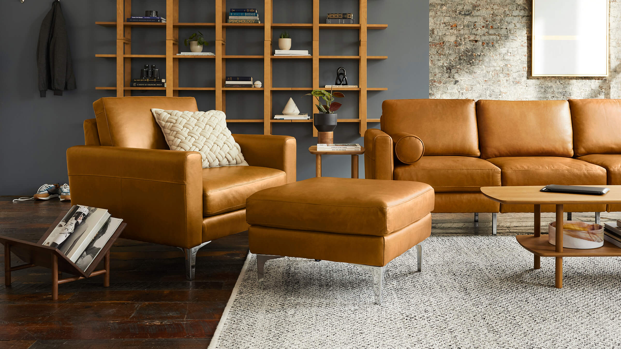 modern living room with brown leather sofas, matching wooden coffee table, and matching ottoman on gray rug