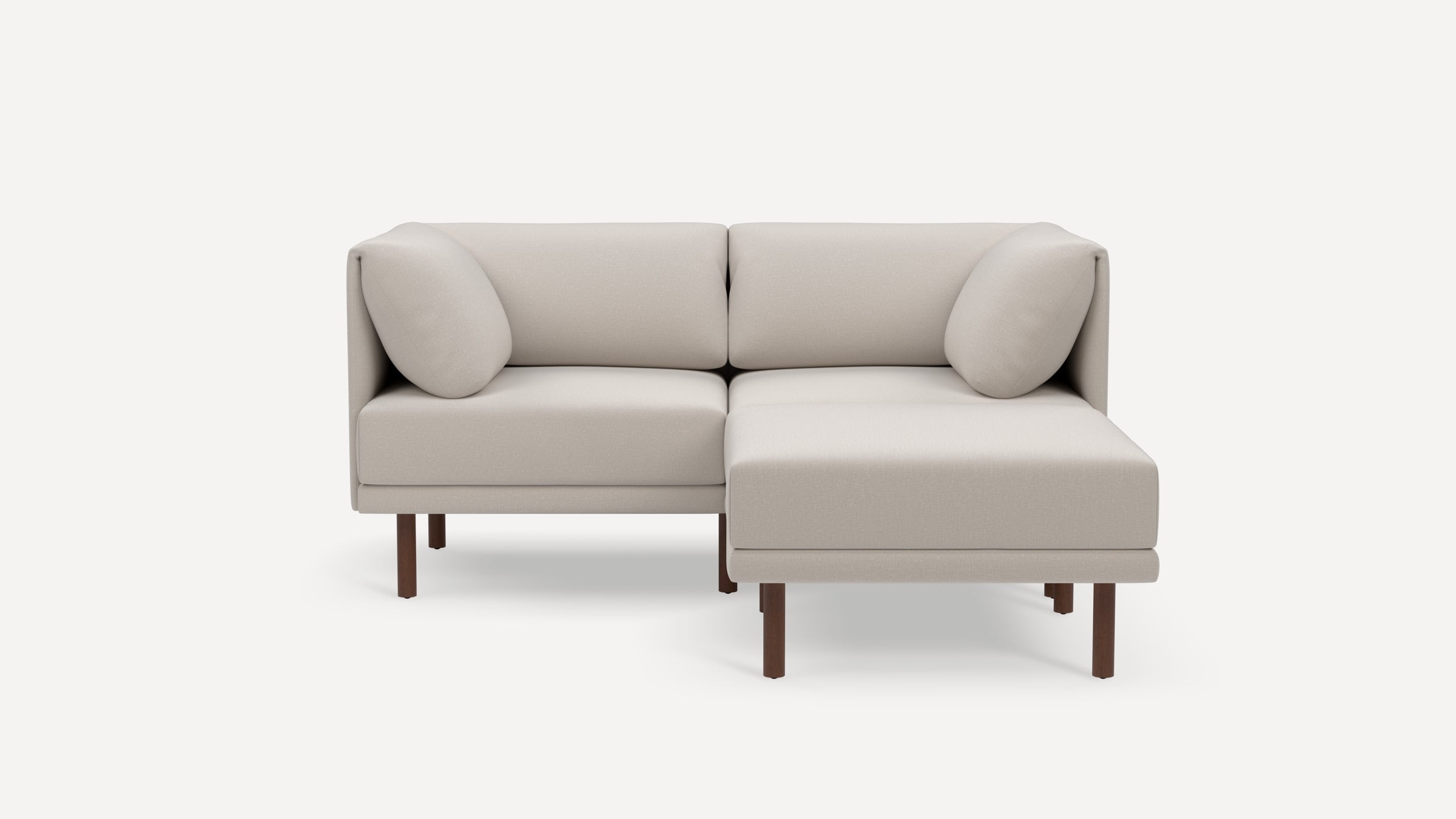 Modern beige sectional sofa with clean lines, wooden legs, and two matching throw pillows on a white background.