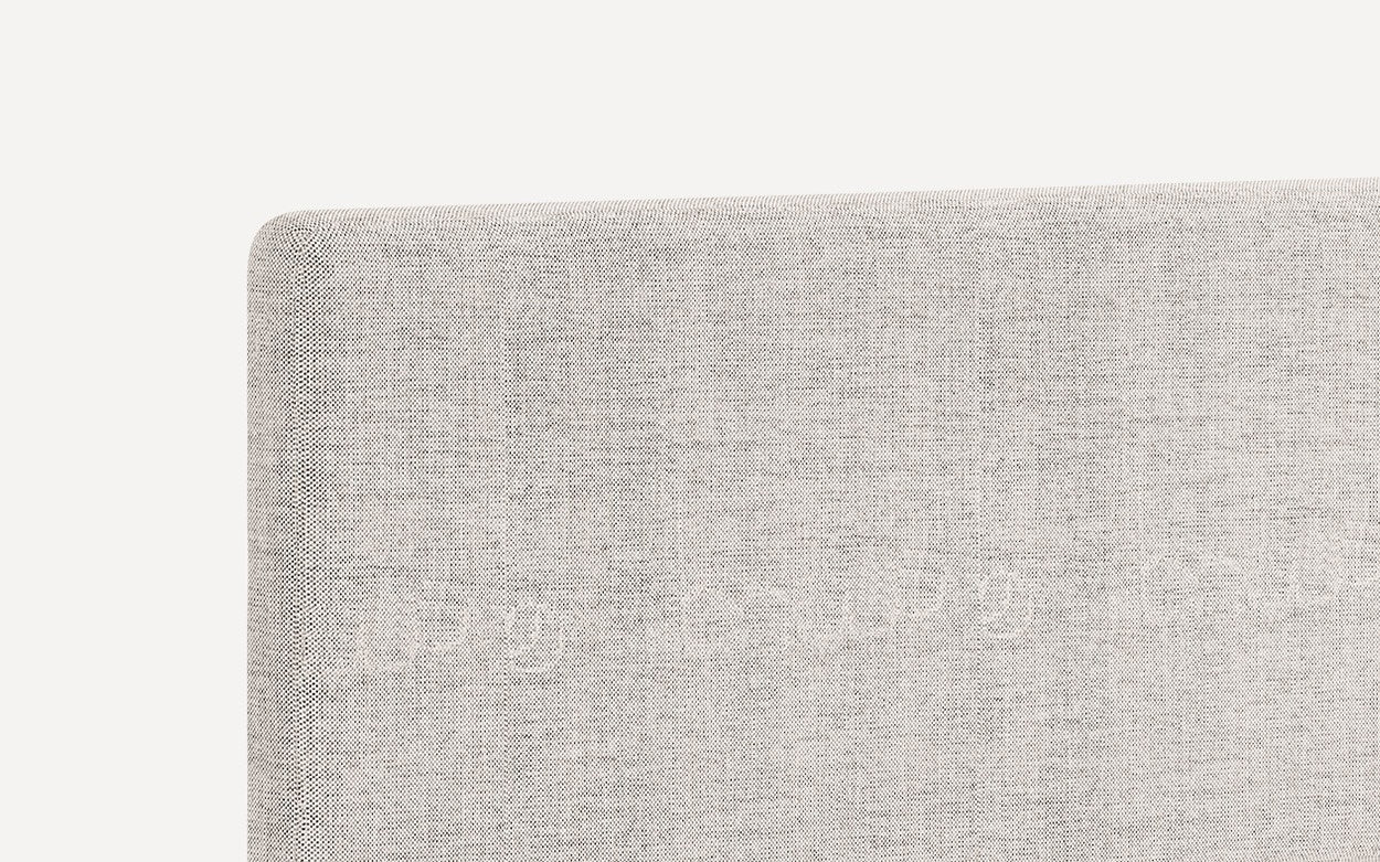 Close-up of a light gray textured fabric headboard with clean, rounded edges and a modern minimalist design.