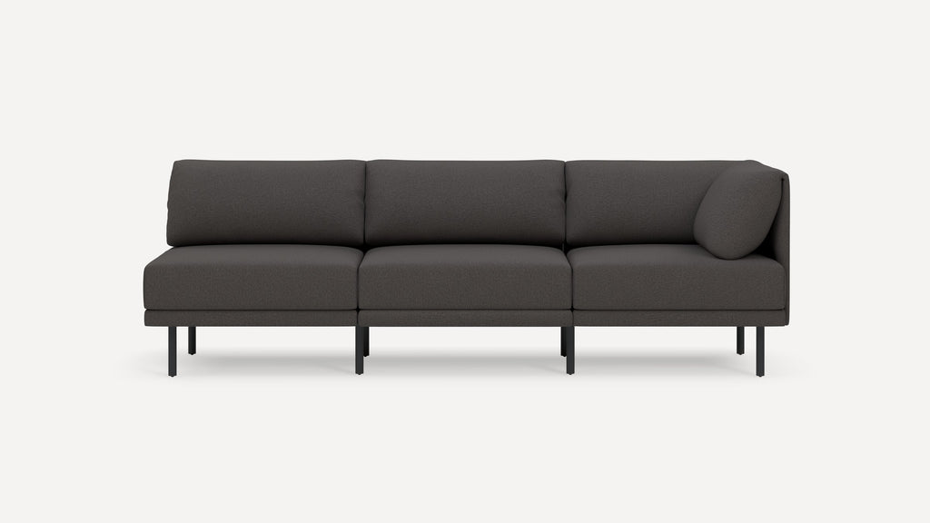 Three-seater modern dark gray sofa with clean lines, slim black metal legs, and a cylindrical cushion on the right armrest.