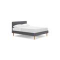 modern gray upholstered bed with wooden legs and white sheets on top of bed, isolated against a black background