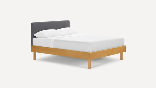 Modern platform bed with light wood frame and dark gray upholstered headboard, dressed in white bedding and pillows.
