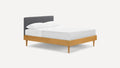 Modern platform bed with light wood frame, tapered legs, and dark gray upholstered headboard, dressed in white bedding.