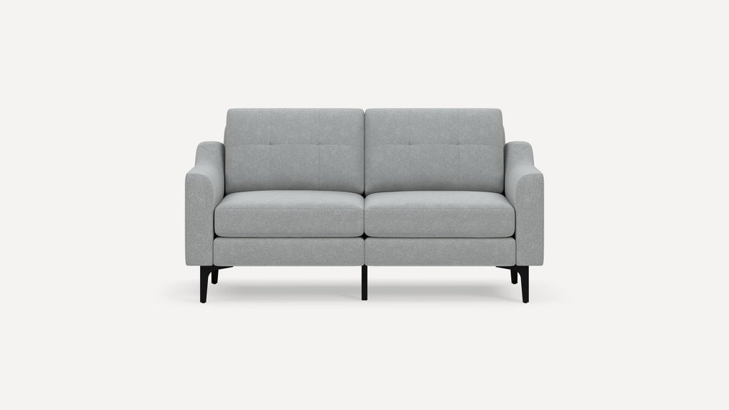 Modern light gray fabric two-seater sofa with low arms, tufted back cushions, and black angled metal legs on a white background.