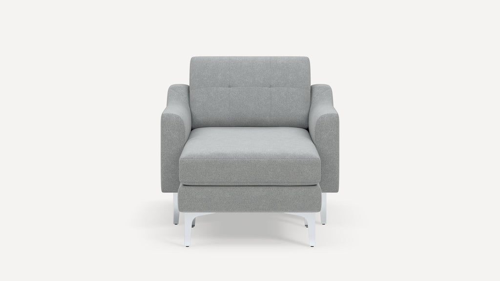 Front view of a modern, light gray upholstered armchair with white metal legs and slightly curved armrests.