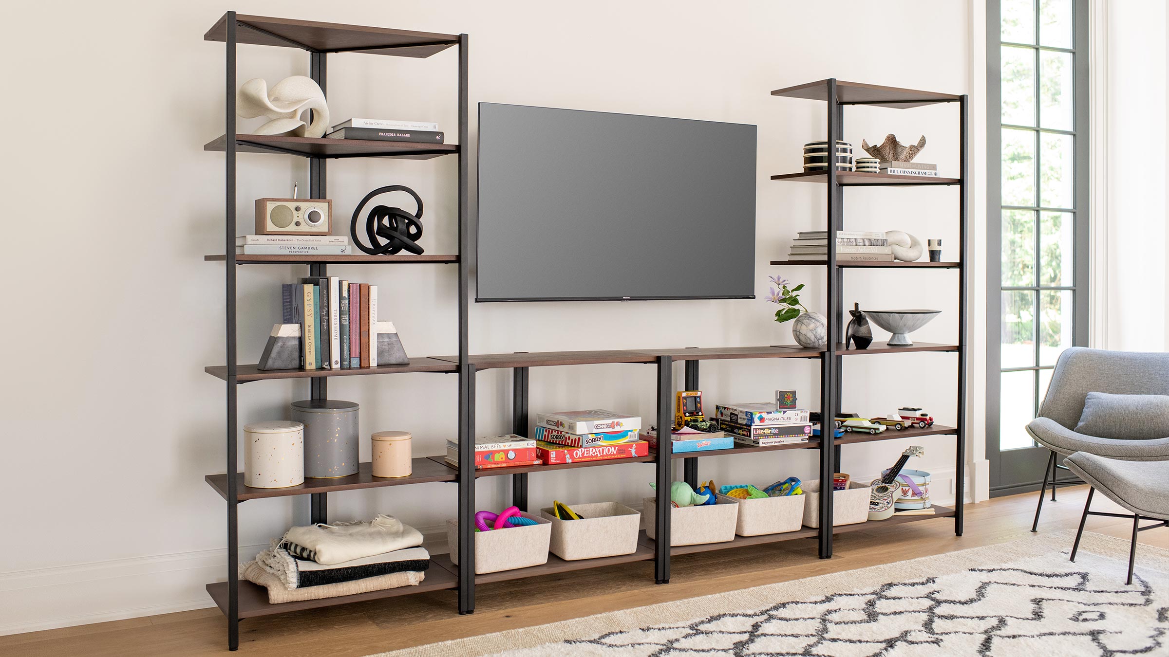 a living room with a tv, bookshel, and a gray chair
