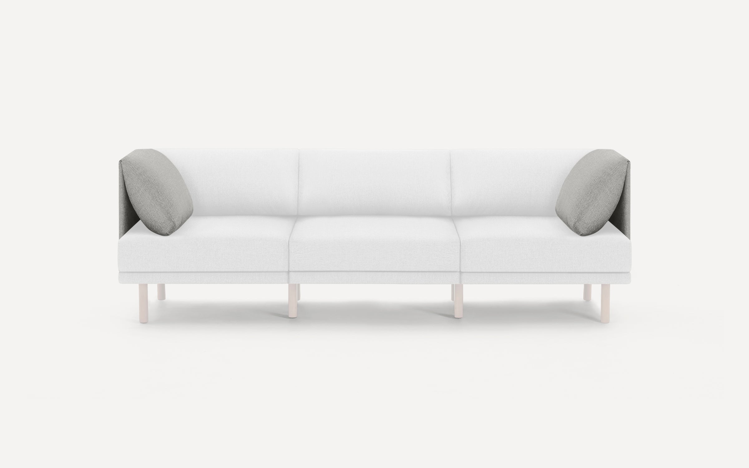 Modern three-seater sofa with white upholstery, light wooden legs, and two gray accent pillows on each end.