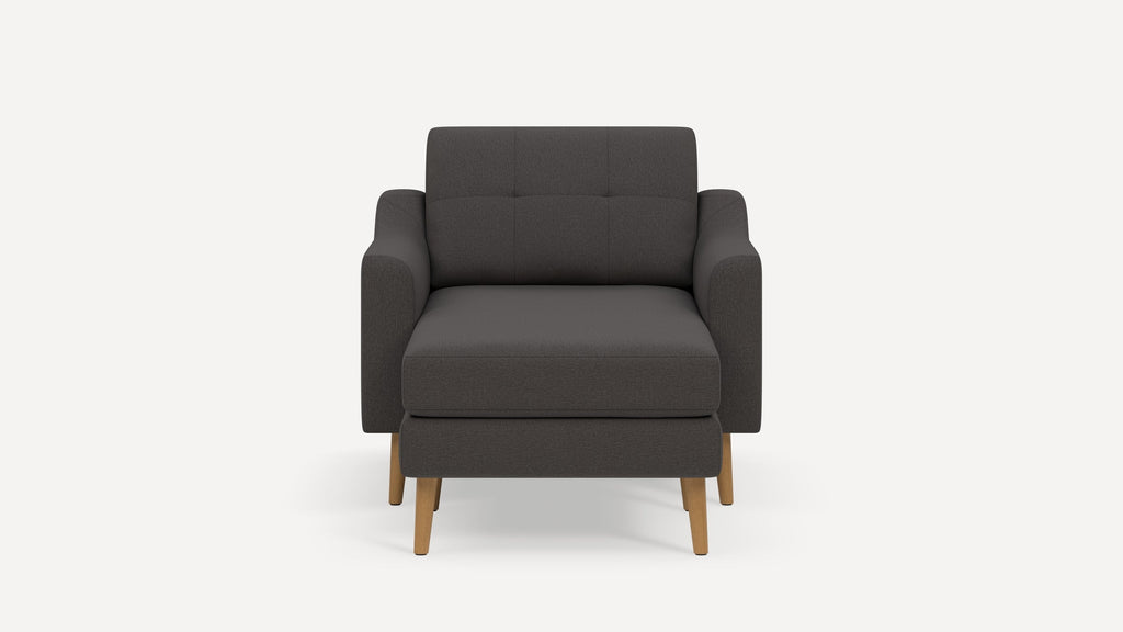 Dark gray upholstered armchair with wooden legs, tufted backrest, and a cushioned seat, shown front-facing.