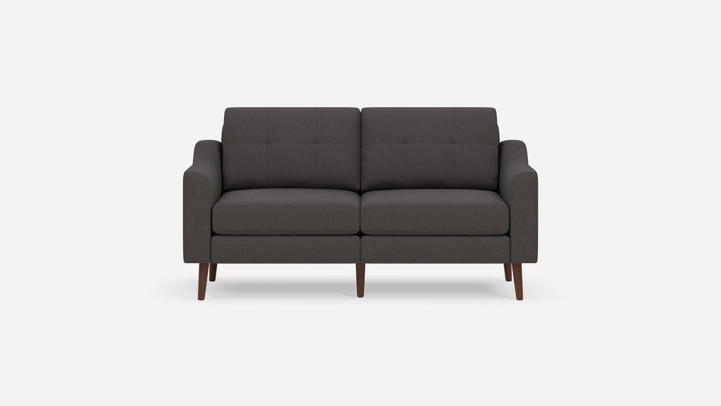 Modern dark gray fabric loveseat sofa with tufted back cushions and wooden tapered legs on a white background.