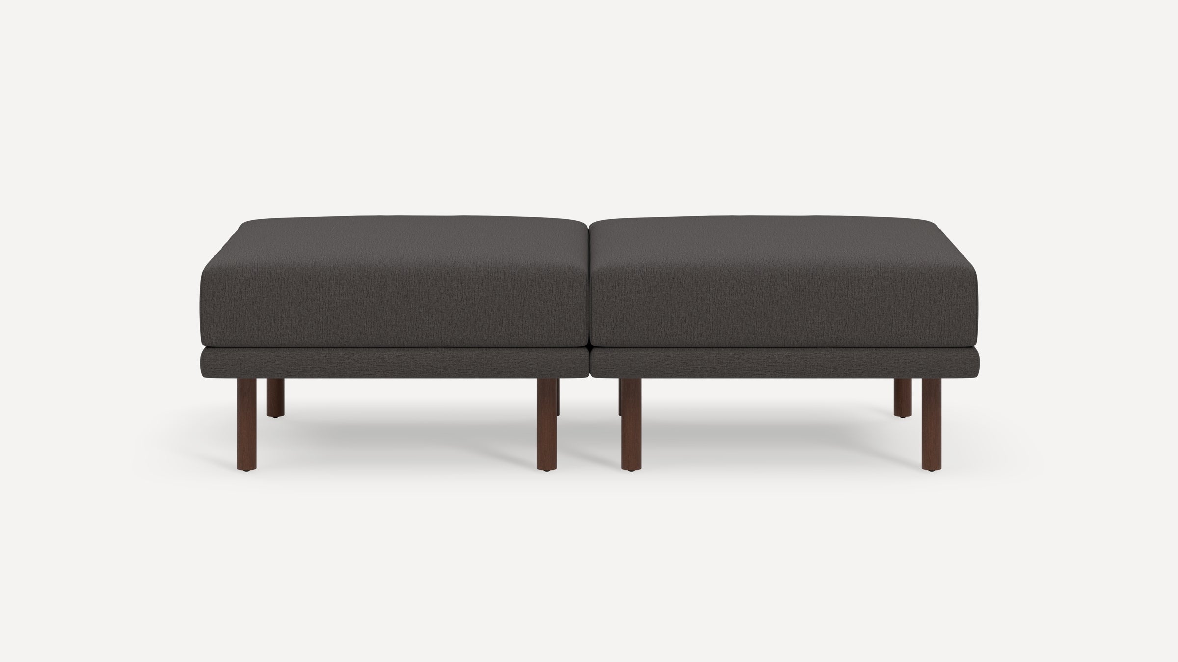 Dark gray upholstered modern rectangular ottoman with wooden legs, consisting of two connected cushioned seats.