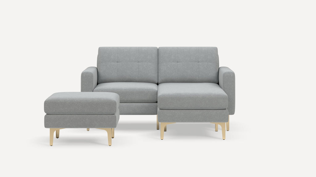 Light gray modern sectional sofa with matching ottoman, gold metal legs, and minimalist design on white background.