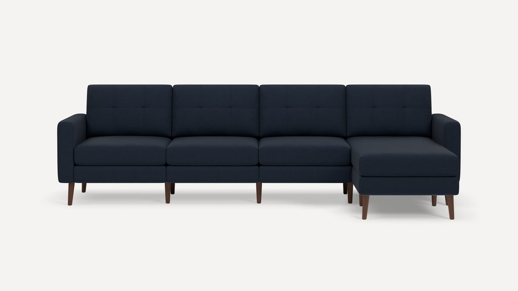 Modern navy blue sectional sofa with four seats, tufted cushions, and wooden legs in a minimalist design.